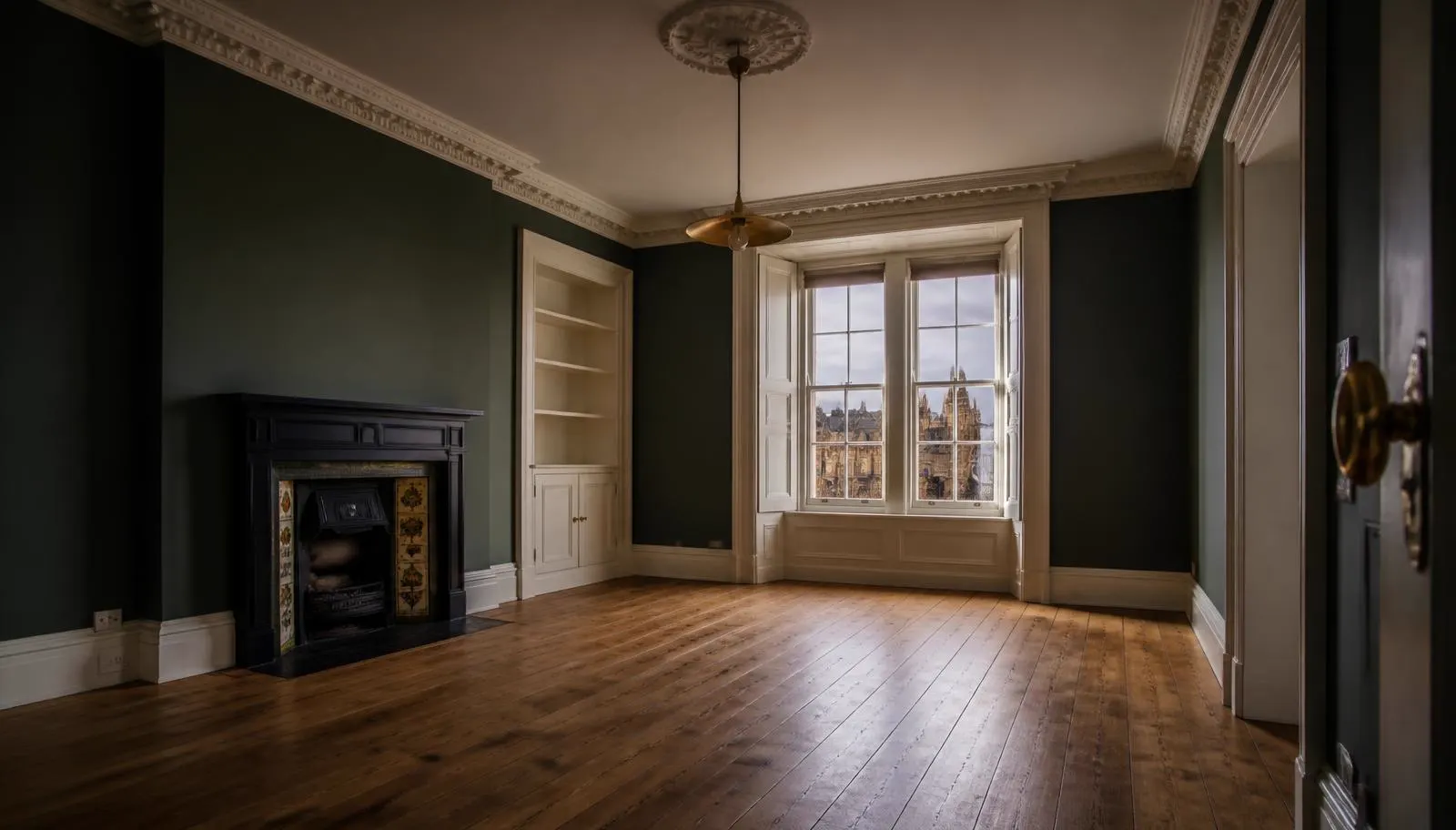 Completed void refurbishment of a pre-1919 Edinburgh tenement room with restored cornicing, cast-iron fireplace and bare timber floor